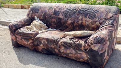 shredded fabric sofa on side of road for clearance collection