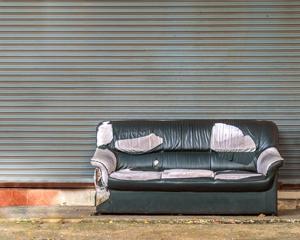old black leather sofa waiting to be collected from street