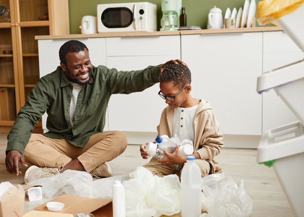 man on kitchen floor with son doing recycling in green ethical home